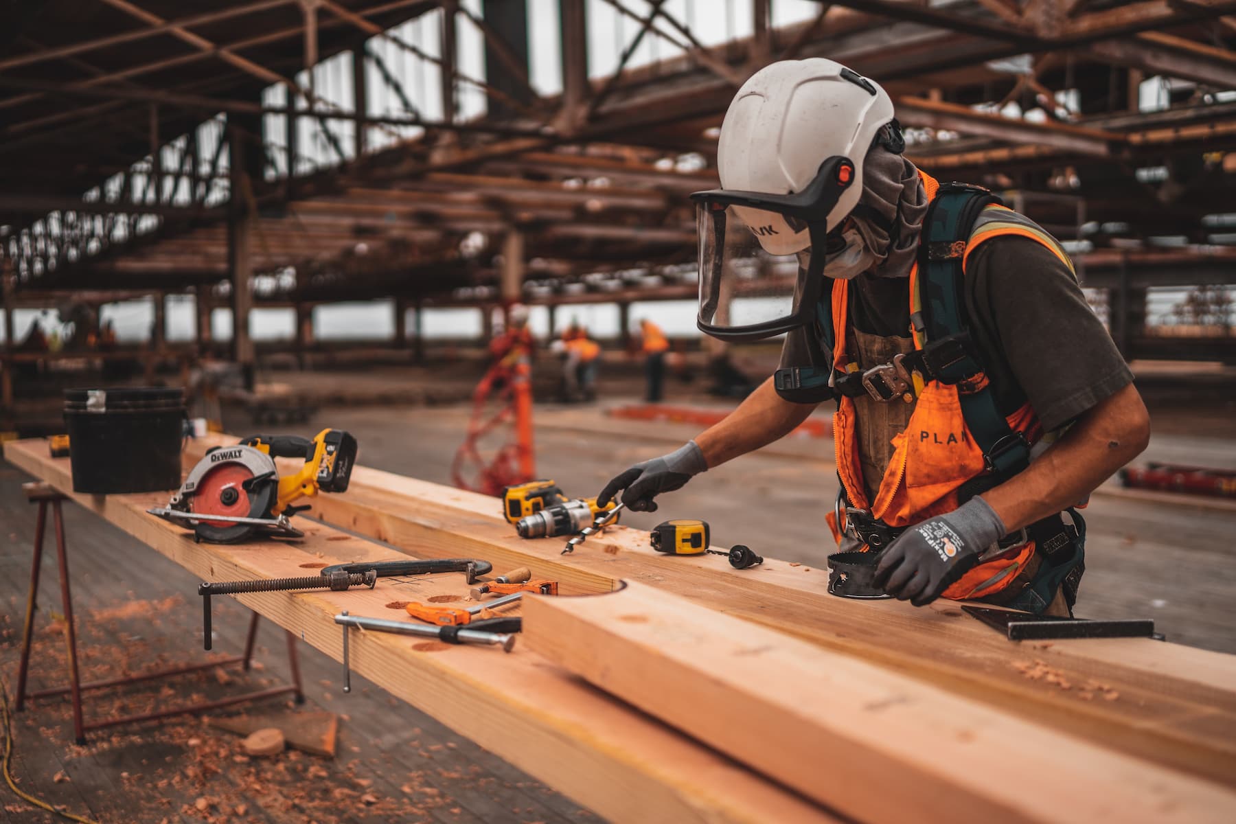 A man using power tools on some timber, wearing full PPE.